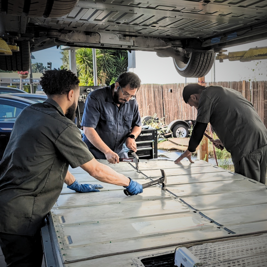Certified technicians repairing a Tesla high-voltage battery at Toyota and Tesla Service Center in Santa Clara